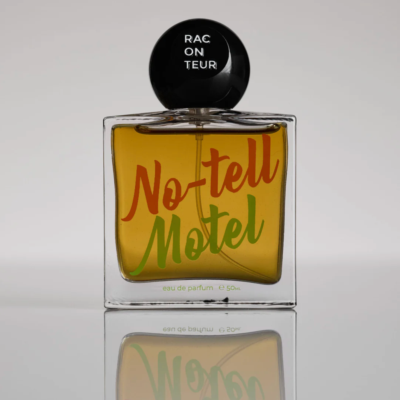 Perfume bottle labeled 'No-tell Motel' with a black cap on a reflective surface.